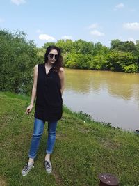 Young woman standing by tree against sky