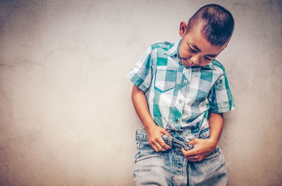 Cute boy standing against wall