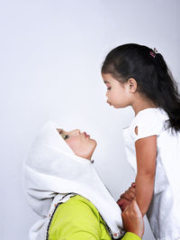 Side view of mother with daughter against wall