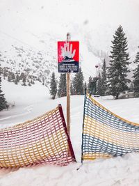 Road sign by frozen trees against sky