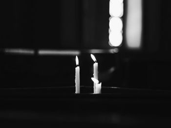 Close-up of illuminated candles in darkroom