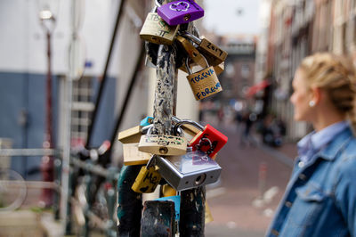 Close-up of padlocks hanging on railing with woman standing in background