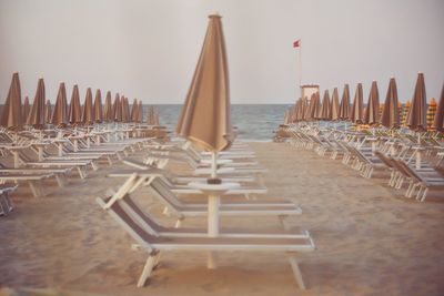 Chairs and tables on table at beach against sky