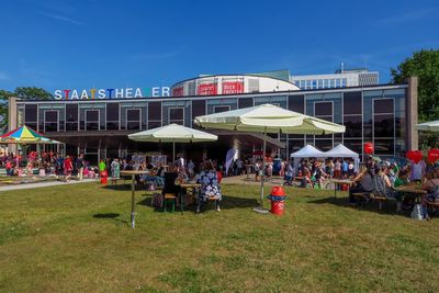 People sitting on grassland against buildings