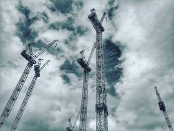 Low angle view of cranes at construction site against sky