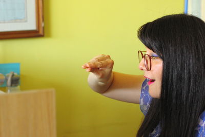 Portrait of young woman against wall