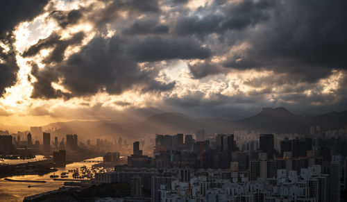 Aerial view of buildings in city against dramatic sky