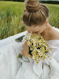 Midsection of woman with flowers on field