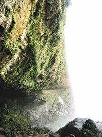 Close-up of waterfall by cliff against sky