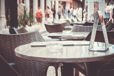 Empty chairs and tables arranged at sidewalk cafe