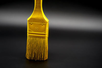 Close-up of yellow candle on table against black background