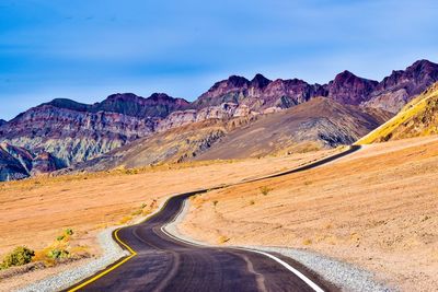 Scenic view of road by mountains against sky