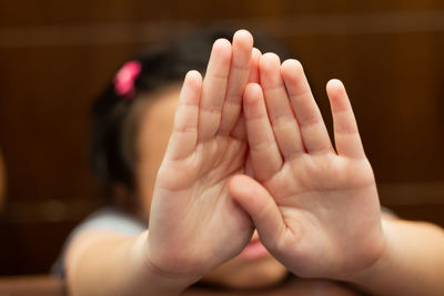 Close-up of girl covering face with hands