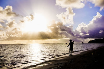 Man in sea against sky during sunset