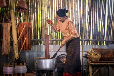 Side view of woman dyeing wool in container at factory