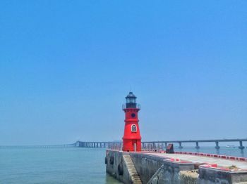 Lighthouse on beach against blue sky