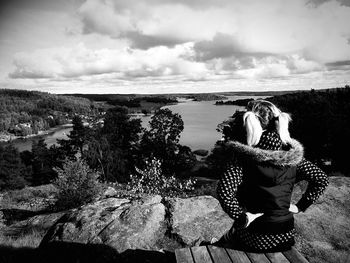 Rear view of woman looking at river against sky