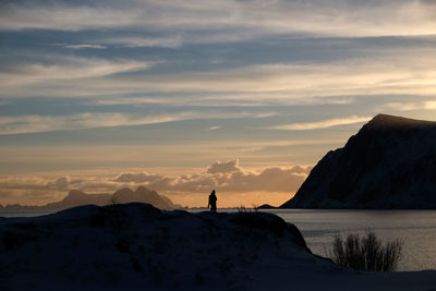 Silhouette man standing by sea against sky during sunset