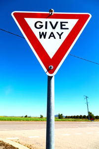 Close-up of road sign against clear blue sky