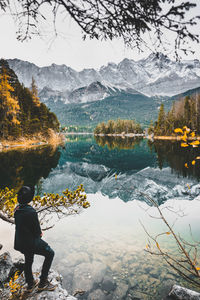 Rear view of man standing on rock by lake