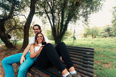 Portrait of young woman sitting on bench in park