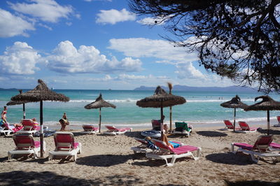 People amidst lounge chairs and parasols on beach