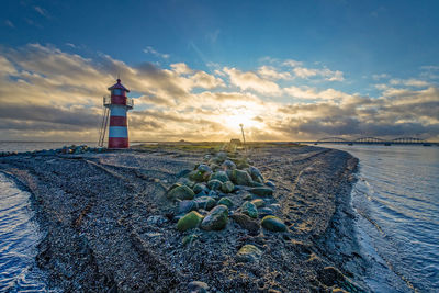 Lighthouse by sea against sky