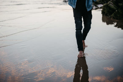 Low section of woman walking at beach during sunset