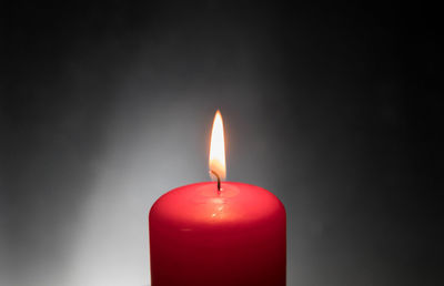 Close-up of lit candle against black background