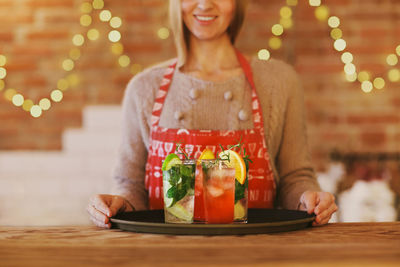 Midsection of woman with drinks on table in party