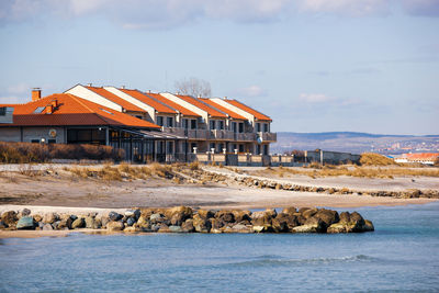 View of buildings by sea against sky