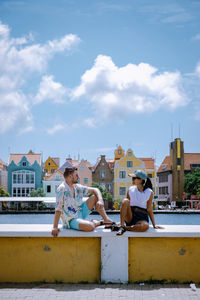 People sitting on swimming pool against buildings