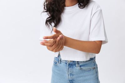 Midsection of woman standing against white background