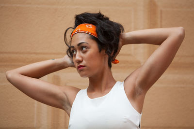 Woman with hand in hair against wall