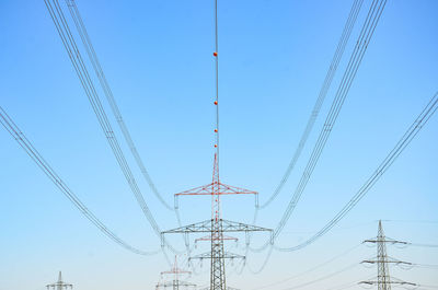 Low angle view of electricity pylon against blue sky