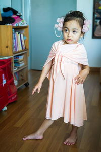 A little girl is standing in a beautiful dress with hair accessories. pretend play at home.