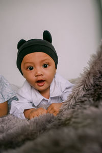 Portrait of cute baby boy lying on bed at home