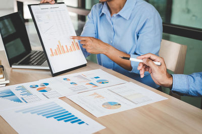 Low section of colleagues discussing over charts at office