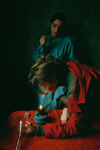 Portrait of young woman standing against black background