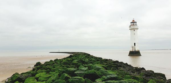 Lighthouse by sea against sky