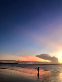 Silhouette man on beach against sky during sunset