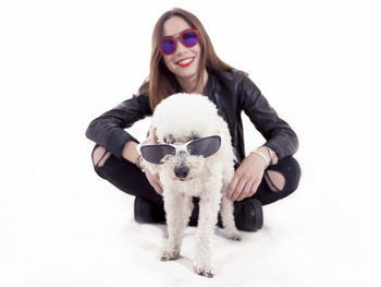 Portrait of smiling young woman with dog against white background