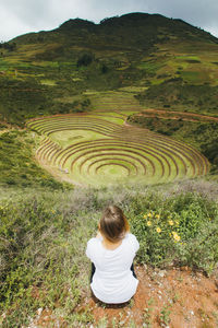 A young woman is sitting near the famous peruvian spot moray in peru