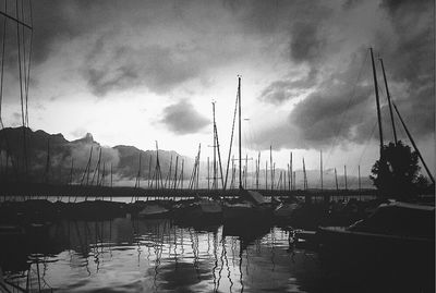 Boats in harbor against cloudy sky