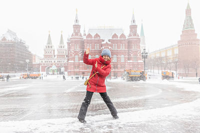 Full length of woman standing on snow covered city in winter