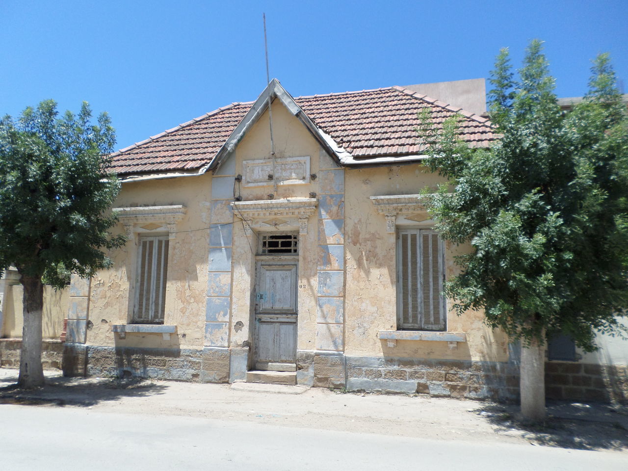 EXTERIOR OF OLD BUILDING BY TREES AGAINST SKY