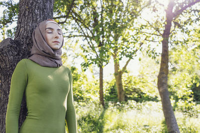 Portrait of woman standing against trees