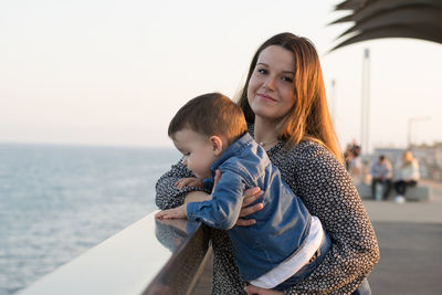 Mother and daughter at shore against sea