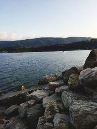 Rocks by sea against clear sky