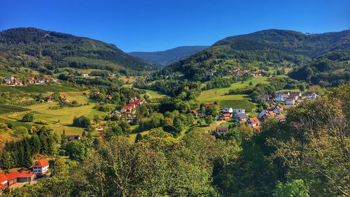 Scenic view of trees and houses by mountains against sky